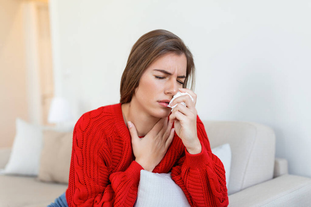 Sick desperate woman has flu. Rhinitis, cold, sickness, allergy concept. Pretty sick woman has runnning nose, rubs nose with handkerchief. Sneezing female. Brunette sneezing in a tissue - Foto, imagen