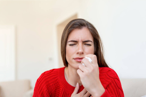 Sick desperate woman has flu. Rhinitis, cold, sickness, allergy concept. Pretty sick woman has runnning nose, rubs nose with handkerchief. Sneezing female. Brunette sneezing in a tissue - Foto, immagini