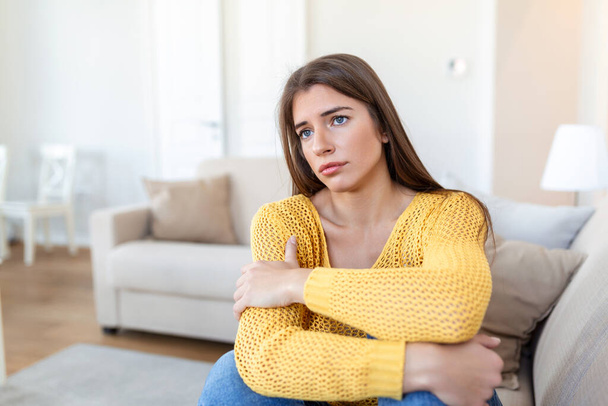 anxious worried woman sitting on couch at home. Frustrated confused female feels unhappy, problems in personal life, quarrel break up with boyfriend and unexpected pregnancy concept - Fotó, kép