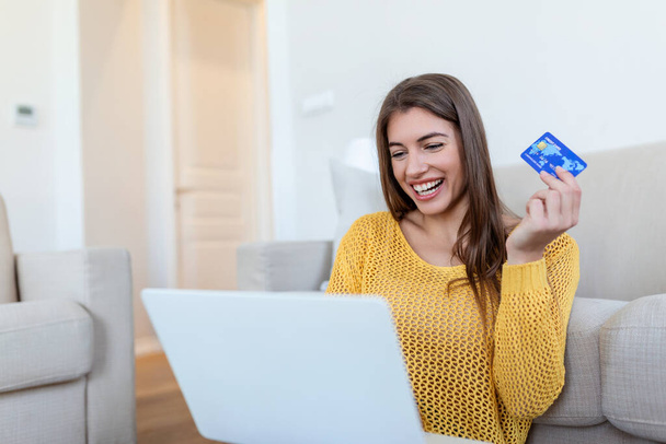 Güzel bir kadının kredi kartıyla alışveriş yaptığını gösteren bir fotoğraf. Kredi kartı tutan ve laptop kullanan bir kadın. Çevrimiçi alışveriş kavramı - Fotoğraf, Görsel
