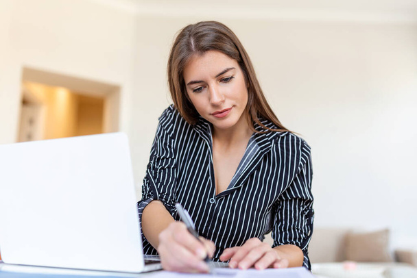 Дистанційна робота, технології та люди концепції - щаслива посміхаючись молода бізнес-жінка з ноутбуком і папери працюють в офісі під час кризи охорони здоров'я Ковід-19. - Фото, зображення