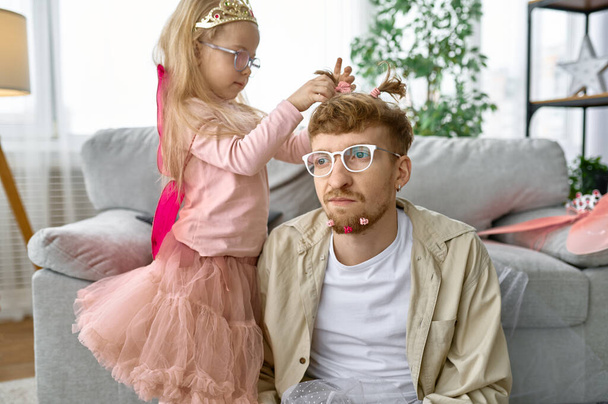 Дочка створює смішну зачіску для батька, щасливий сімейний момент і батьківське задоволення
 - Фото, зображення