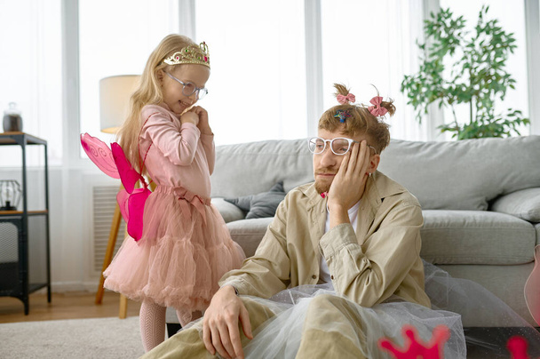 Tired fatigue father wearing funny costume having fun with excited cheerful daughter at home - Photo, Image