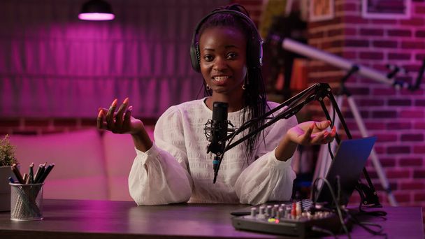 Afro-Amerikaanse vrouw vlogger praten met publiek tijdens het opnemen van podcast met behulp van audio mixer en microfoon. Beroemde influencer het creëren van inhoud voor online social media pagina van podcasting studio. - Foto, afbeelding
