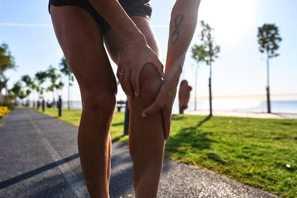 Injuries - sports running knee injury on woman. young woman with injured knee or leg outdoors - Foto, Imagem