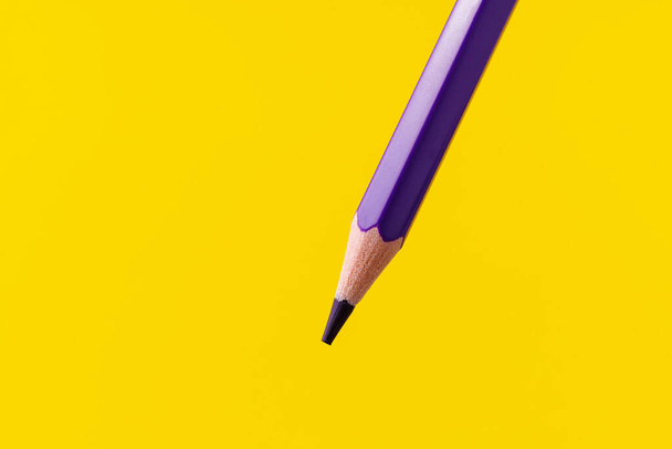Kleurpotlood close-up met selectieve focus op de stylus en een wazige gele achtergrond. Kopieer ruimte voor tekst. - Foto, afbeelding