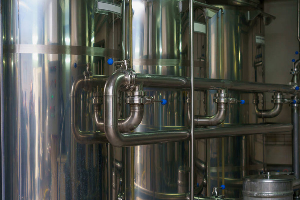 A stainless steel pipe system in the food industry at a brewery in the process of brewing beer. Background with selective focus and copy space for text - Fotó, kép