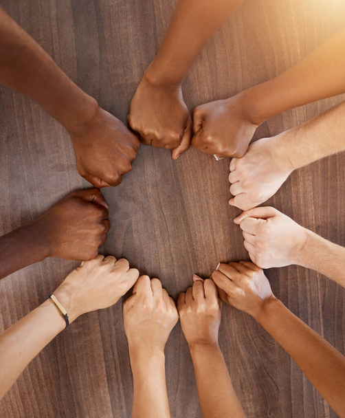 Hands, collaboration and motivation with the fists of a team in a circle or huddle on a wooden background from above. Teamwork, goal and target with a group of people ready for success in unity. - Foto, immagini