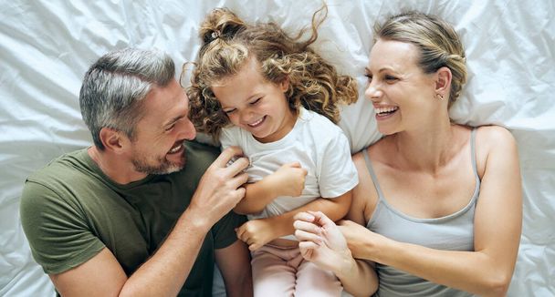 Bed, love and family bonding, relax and having fun laughing and being playful in a bedroom together from above. Smile, play and happy child enjoy waking up in morning with playful, young parents. - Fotoğraf, Görsel