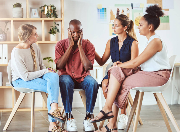 Community, mental health and support with group comfort colleague after bad news or fired at work. Care, unity and kindness by diverse people showing concern and love for depressed man in an office. - Photo, image