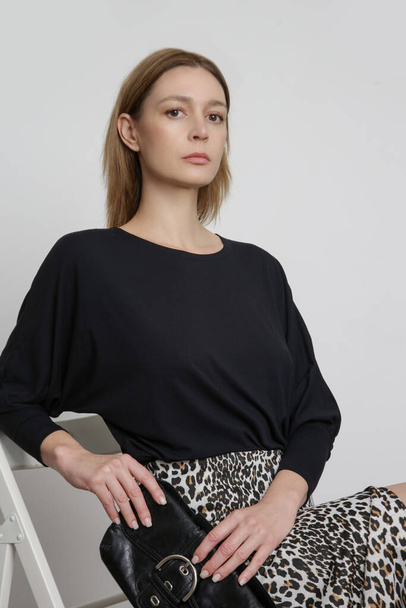 Serie of studio photos of attractive young female model wearing black blouse and leopard printed midi skirt. - Photo, Image