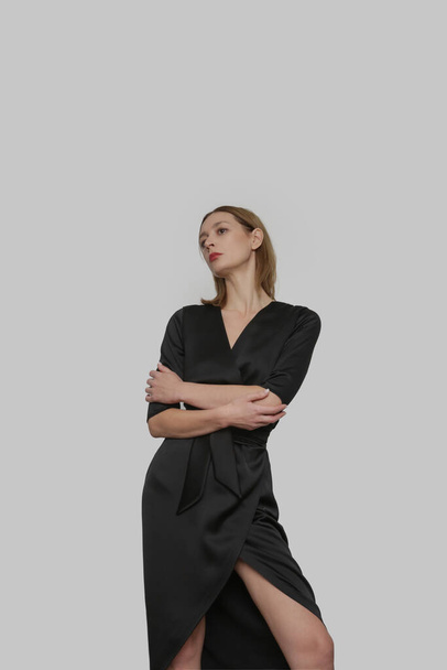 Serie of studio photos of attractive young woman wearing elegant black silk satin dress. - Fotó, kép