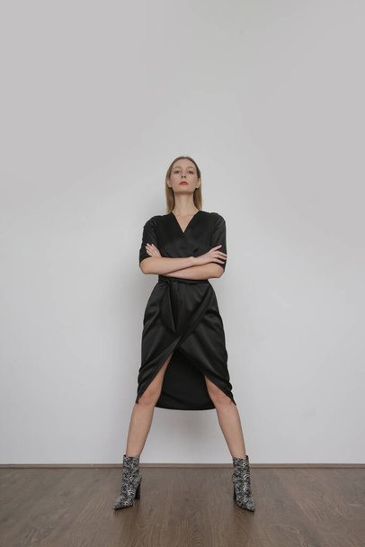 Serie of studio photos of attractive young woman wearing elegant black silk satin dress. - Фото, зображення