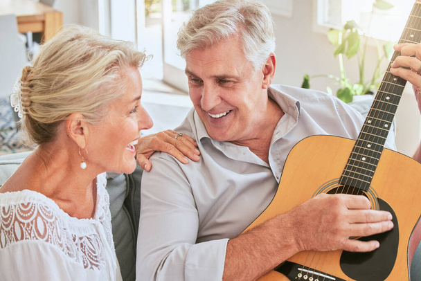 Ζευγάρι ηλικιωμένων με κιθάρα για μουσική και τραγούδι μαζί στον καναπέ για τον τρόπο ζωής συνταξιοδότησης και καλοκαιρινή φωτοβολίδα φακού. Ευτυχισμένη ηλικιωμένη γυναίκα ή δημιουργικός μουσικός άνθρωποι στο σαλόνι σπίτι παίζοντας ερωτικό τραγούδι. - Φωτογραφία, εικόνα