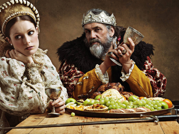 La vie royale peut être fatigante. Une reine ennuyée assise aux côtés de son mari lors d'un banquet - Photo, image
