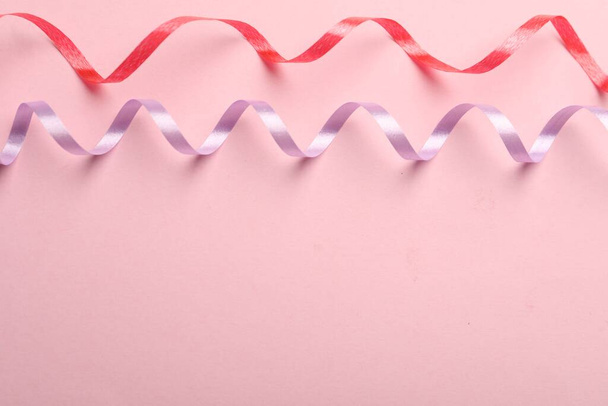 Colorful serpentine streamers on pink background, flat lay. Space for text - 写真・画像