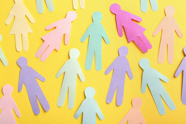 Many different paper human figures on yellow background, flat lay. Diversity and inclusion concept - Foto, imagen