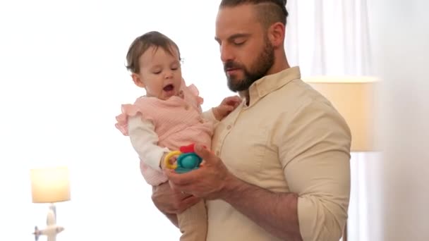 Father talking to newborn baby with toys for healthy growth, language learning and development. Happy, care and love with dad holding child in room or house for maternity and bonding together. - Footage, Video