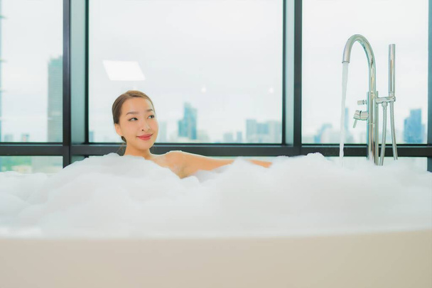 Portret piękna młoda azjatycka kobieta relaks uśmiech wypoczynek w wannie w łazience wnętrza - Zdjęcie, obraz