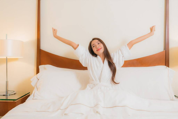 Портрет красива молода азіатка посміхається розслаблятися на ліжку в інтер'єрі спальні
 - Фото, зображення