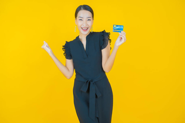 Porträt schöne junge asiatische Frau lächeln mit Kreditkarte auf farbigem Hintergrund - Foto, Bild