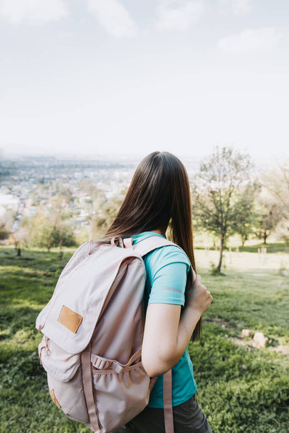 Невпізнавана молода студентка використовує рожевий рюкзак, дивлячись на горизонт з пагорба. Впевненість у собі. Високоякісна фотографія
 - Фото, зображення