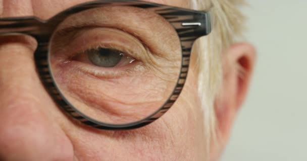 Szemek, látás és szemüveg egy idős ember szemével a szemésznél vagy optikusnál vizsgára vagy tesztre. Nyugdíjba vonulás, ráncok és látás egy idős férfi beteg szemfehérjét és keretet tesztel. - Felvétel, videó