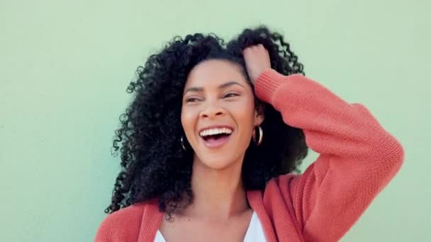 Black woman smile, play with natural hair and happy against green backdrop or wall. Beautiful model girl with healthy curly afro, show expression of happiness against mint green background outside. - Footage, Video