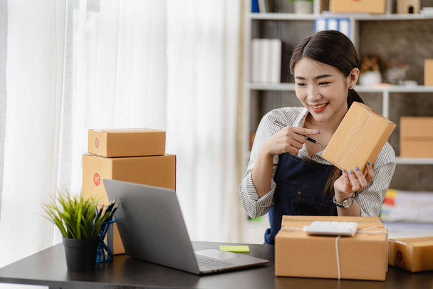gyönyörű ázsiai nő dolgozik otthon eladási online sárga doboz és laptop, hogy név megrendelések ügyfelek sme üzleti koncepció csomagkézbesítés - Fotó, kép