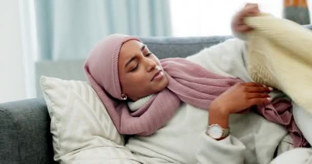 Moslim, menstruatiekrampen en vrouw met buikpijn die op de bank ligt en zich ziek voelt als gevolg van endometriose thuis. Ongelukkig islamitisch persoon met buik, buik en spijsverteringsproblemen als gevolg van menstruatie. - Video