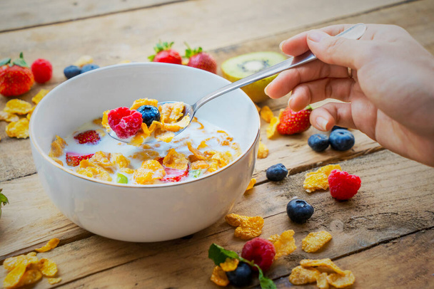 Close up of woman hand holding a spoon while eating cereal in a bowl - Foto, imagen