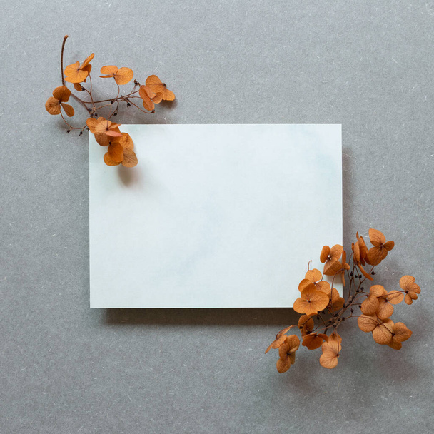 Almohadilla de memorándum en blanco y flores de hortensia marrón sobre fondo gris. vista superior, espacio de copia - Foto, imagen