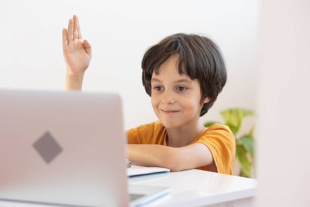 Online afstandsonderwijs. een jongen met een computer communiceert via videoconferentie met een leraar en een klasgroep. Het kind communiceert online. - Foto, afbeelding
