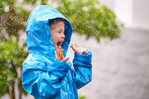 Щоб насолодитися веселкою, спочатку насолоджуйтеся дощем. молода дівчина грає надворі під дощем
 - Фото, зображення