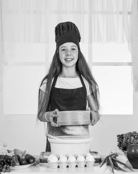 child prepare healthy food at home and wearing cook uniform. housekeeping and home helping. childhood development. small girl baking in kitchen. kid chef cooking with flour. Food with thought. - Foto, afbeelding