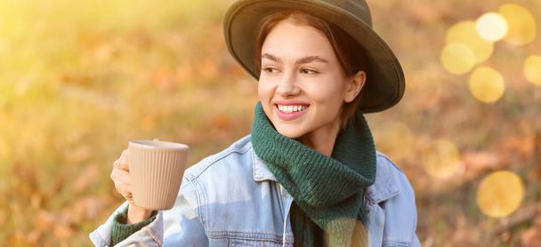 秋の公園で熱いお茶を飲むかなり若い女性 - 写真・画像