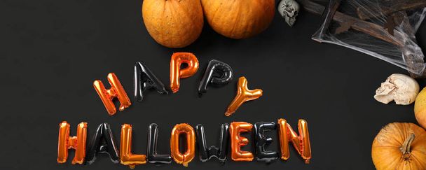 Text HAPPY HALLOWEEN made of balloons, pumpkins, skulls and spiderweb on black background - Photo, Image