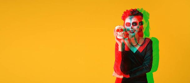 Jovem com crânio pintado em seu rosto para o Dia dos Mortos do México (El Dia de Muertos) contra fundo amarelo com espaço para texto - Foto, Imagem