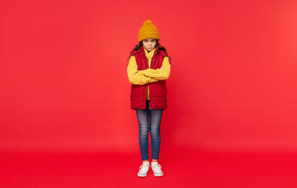 express emotion. winter fashion. unhappy kid with curly hair in hat. female fashion model. teen girl in down vest. full length of child wearing warm clothes. - Fotografie, Obrázek