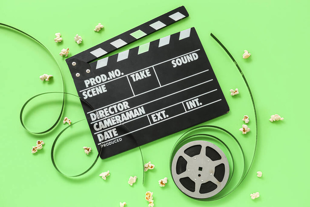 Film clapper met haspel en popcorn op groene achtergrond - Foto, afbeelding