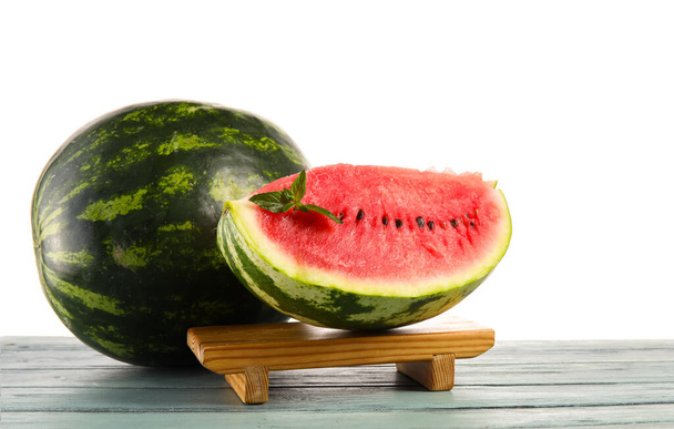 Ständer mit geschnittener Wassermelone und Minze auf Tisch vor weißem Hintergrund - Foto, Bild