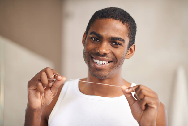 Flossing daily prevents decay. A young man holding dental floss - Foto, Imagem