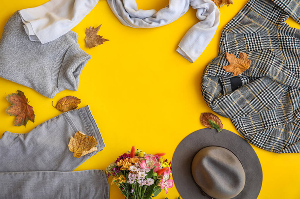 Quadro feito de roupas elegantes, flores, acessórios e folhas de outono no fundo amarelo - Foto, Imagem