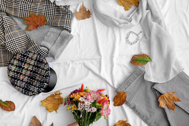 Σκελετός από φθινοπωρινά ρούχα, αξεσουάρ και πεσμένα φύλλα σε λευκό φόντο υφάσματος - Φωτογραφία, εικόνα