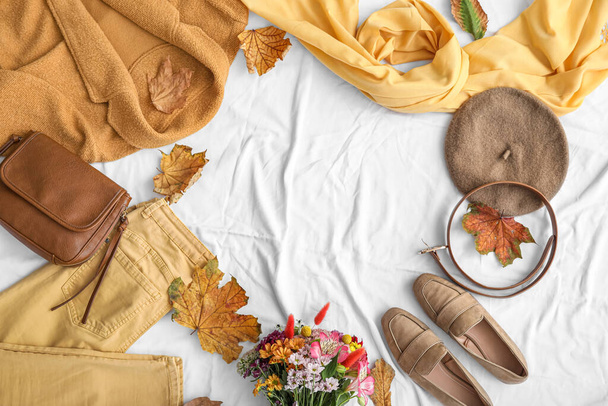 Rahmen aus Herbstkleidung, Accessoires, Schuhen und Laub auf weißem Stoffhintergrund - Foto, Bild