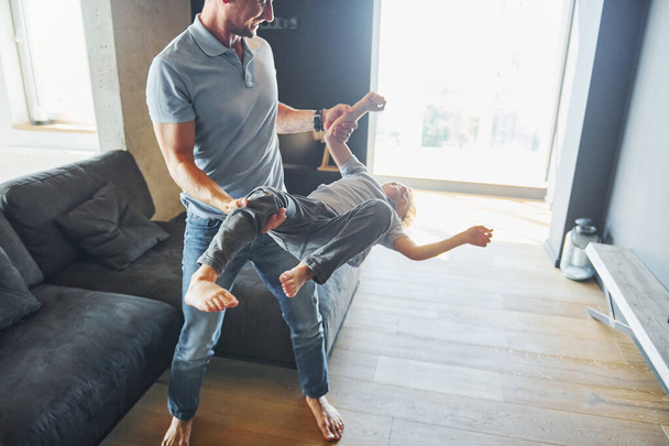 Man holding boy and having fun. Father and son is indoors at home together. - Foto, Bild