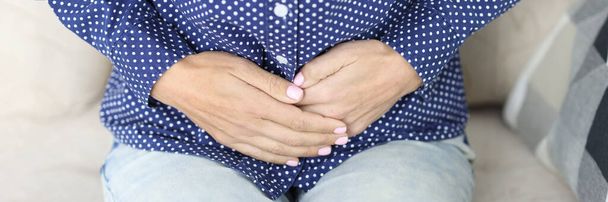 Women hands on stomach with painful spasms. Menstrual pain and cramps concept - Photo, image