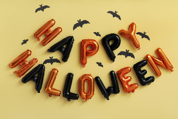 Texto HAPPY HALLOWEEN hecho de globos con murciélagos de papel sobre fondo amarillo - Foto, Imagen