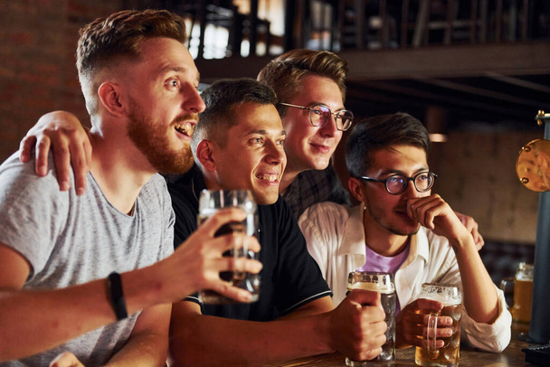 With beer in hands. People in casual clothes sitting in the pub. - Photo, image