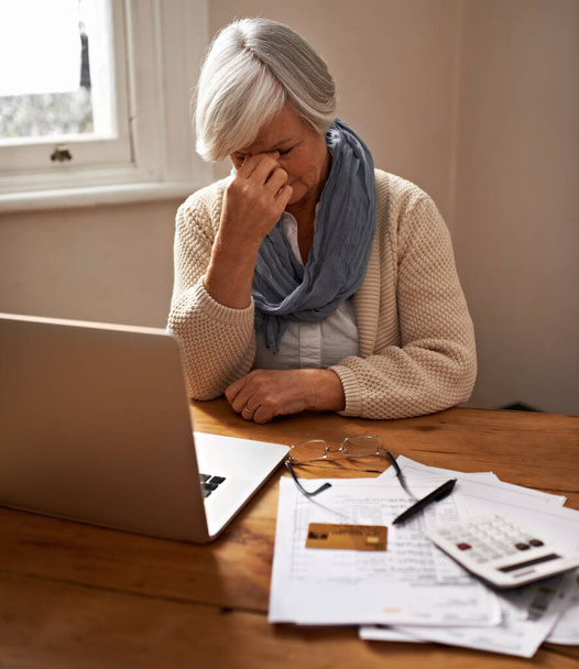 Nyugdíjpénztári gondok... egy idős nő ül a laptopja előtt stresszesnek és aggódónak tűnik. - Fotó, kép